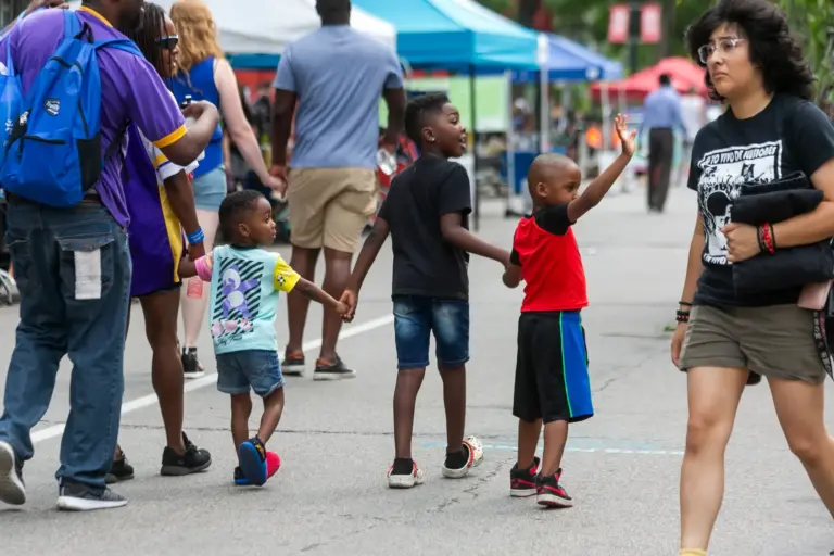 family with kids holding hands and walking down Lake Street during Open Streets. One child is waving