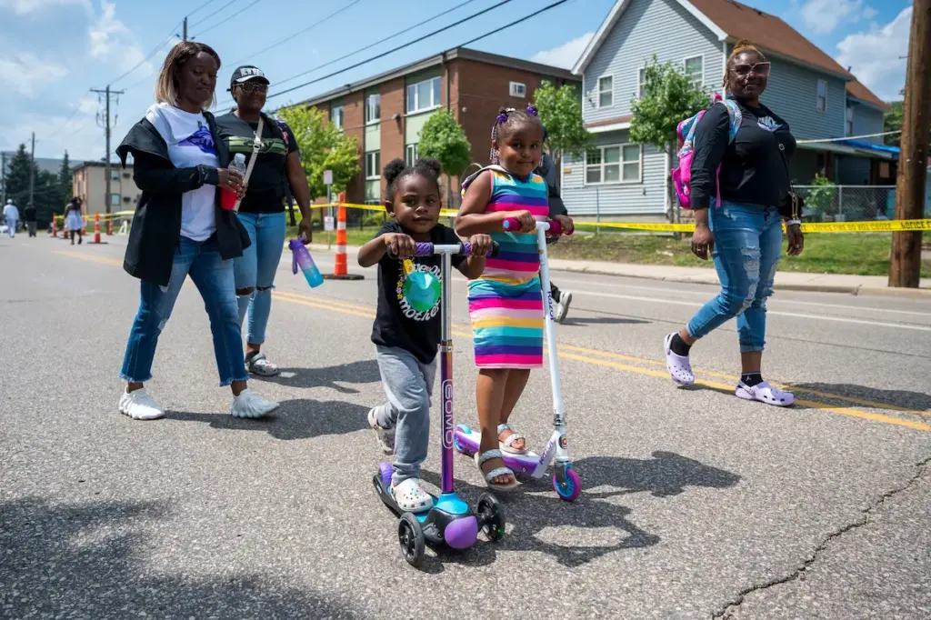 Two young Black girls riding scooters with their family down Glenwood Avenue during Open Streets 2023