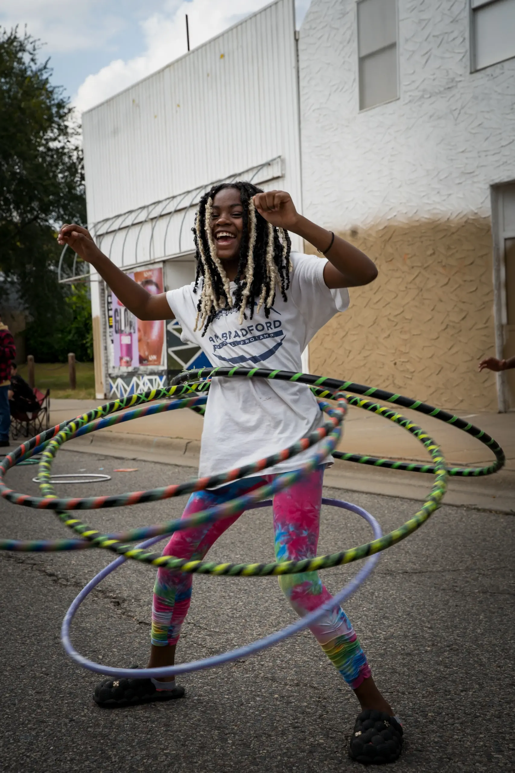 Young black girl hula hooping with multiple hoops and smiling