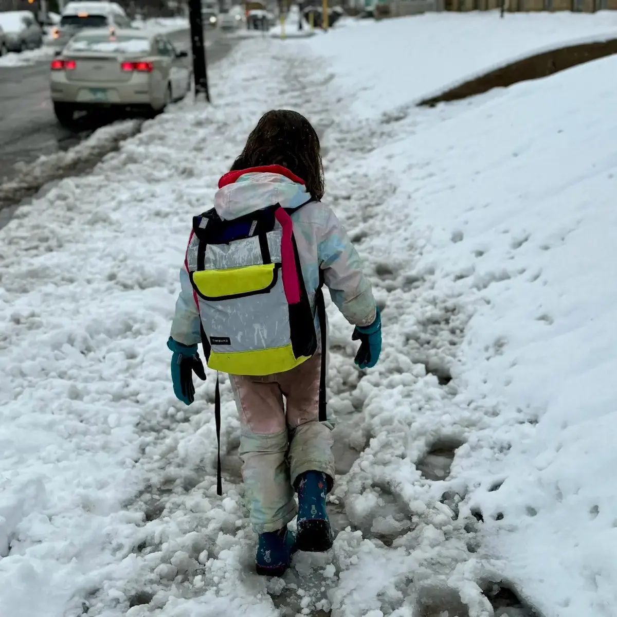 small child walking through unclear sidewalks with snow
