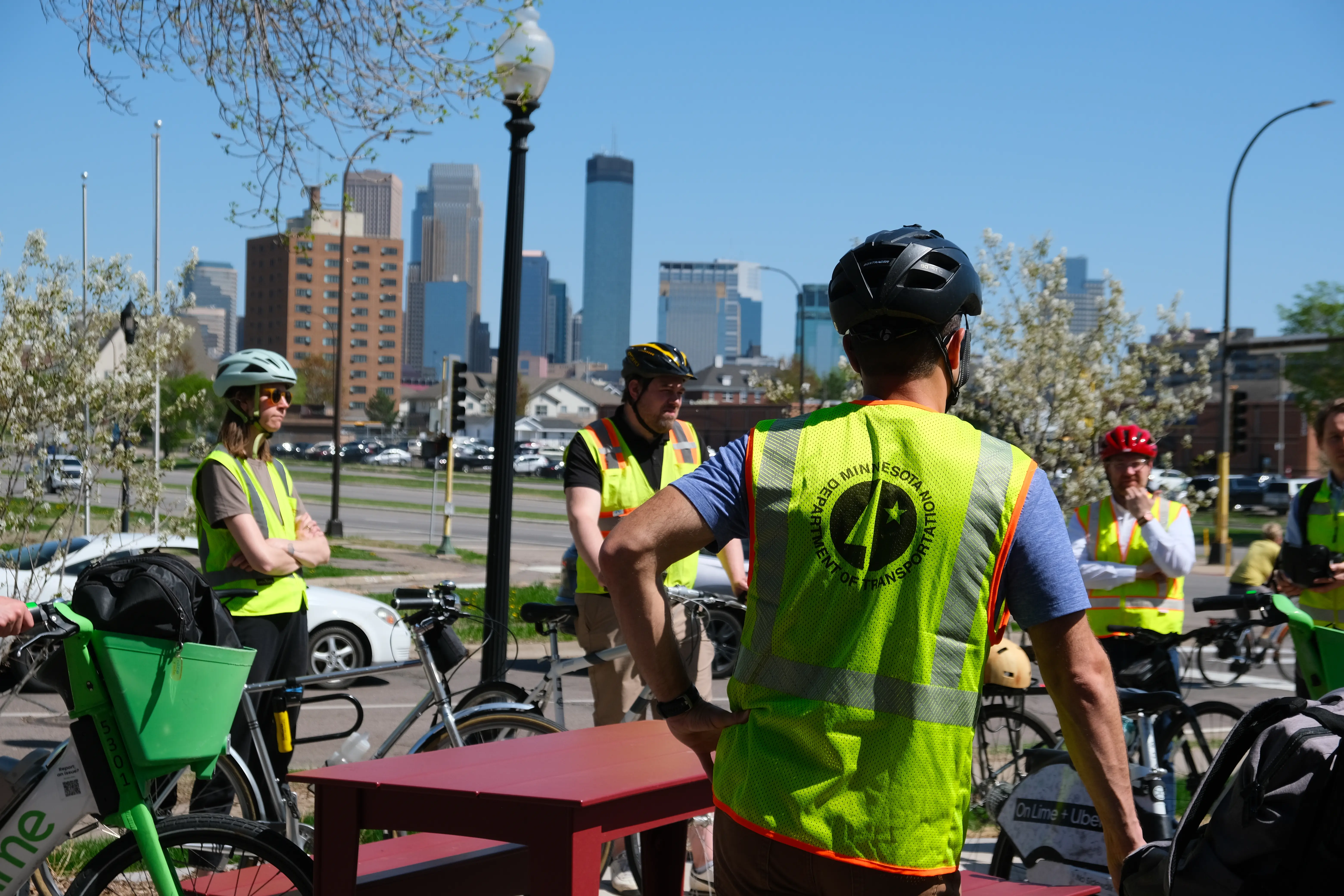 MnDOT employee in helmet on a bike tour with Minneapolis skyline in the background